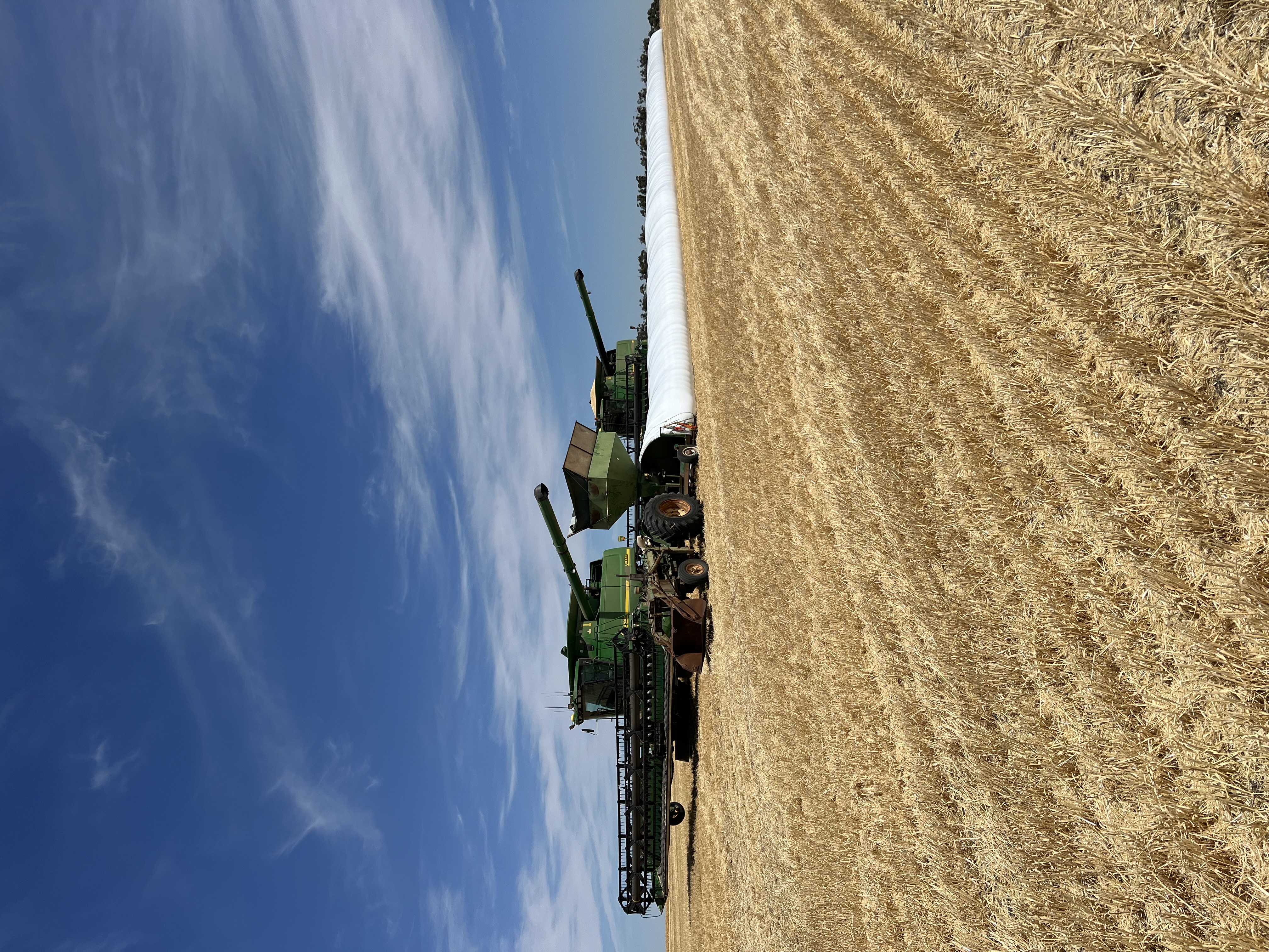 Headers unloading grain into on-farm storage